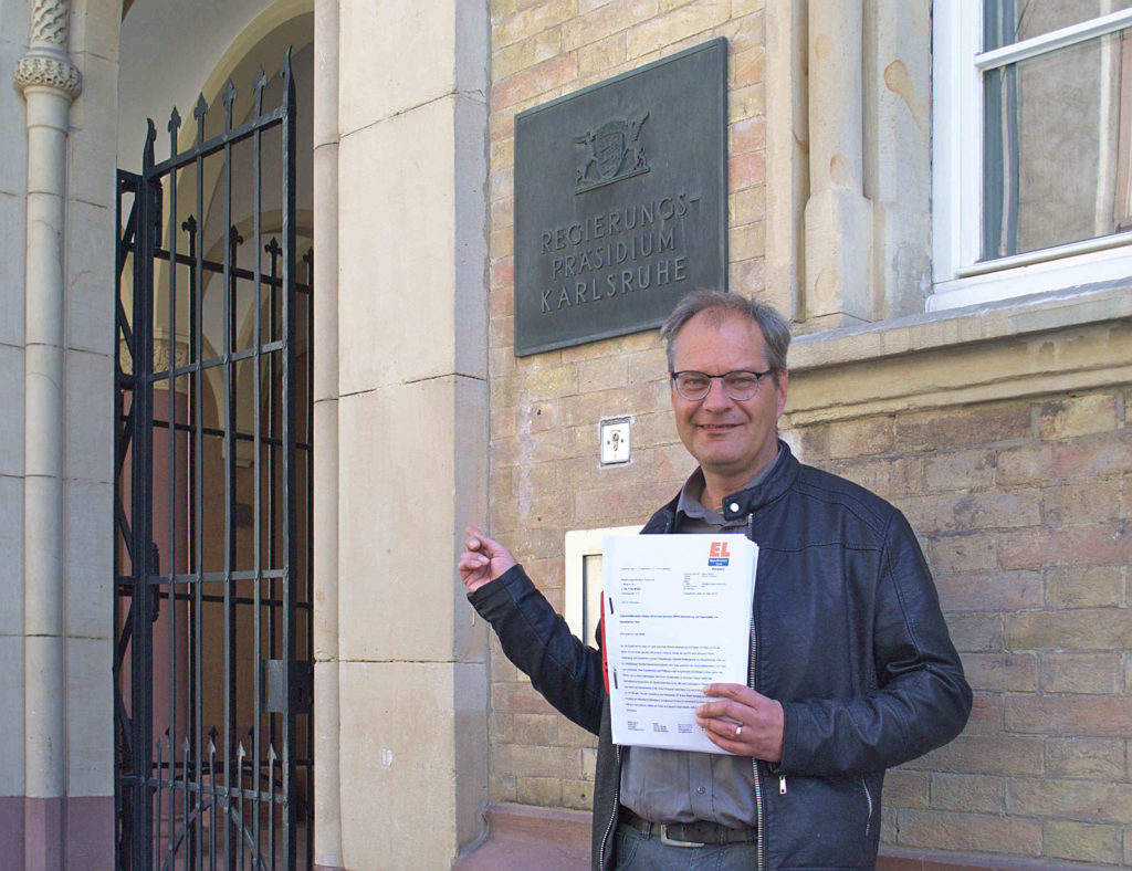 Bernd Binsch mit den gesammelten Unterschriften vor dem Regierungspräsidium Karlsruhe.